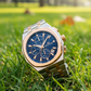 Luxury watch with blue face and rose gold accents on grass